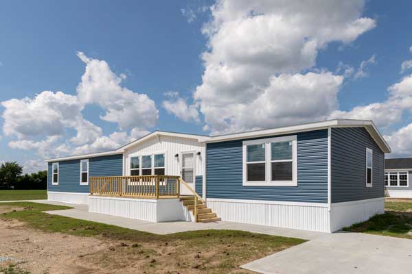 Modern mobile home in a vast, open field under a blue sky, exemplifying a prime candidate for refinancing.