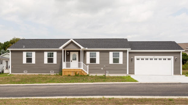 A gray manufactured home with white shutters and a garage