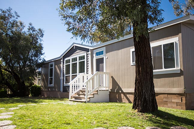 The front of a mobile home in sunlight. Purchasing a used mobile home can be an affordable investment for a buyer looking for housing that fits their lifestyle.
