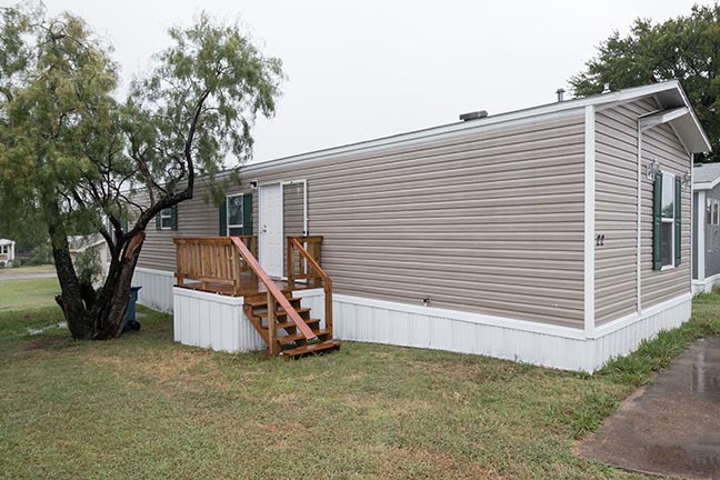 A mobile home with porch steps and a storm door, an example of the great used mobile homes that may be available on the market.