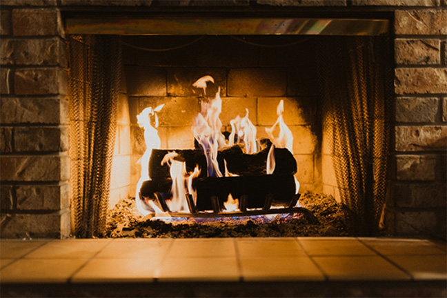 A cozy fire burns in a brick fireplace.