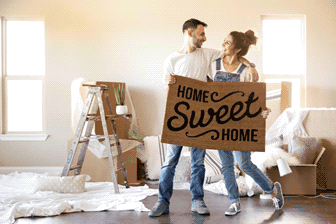 Couple holding up home sweet home doormat and enjoying the value of their new home